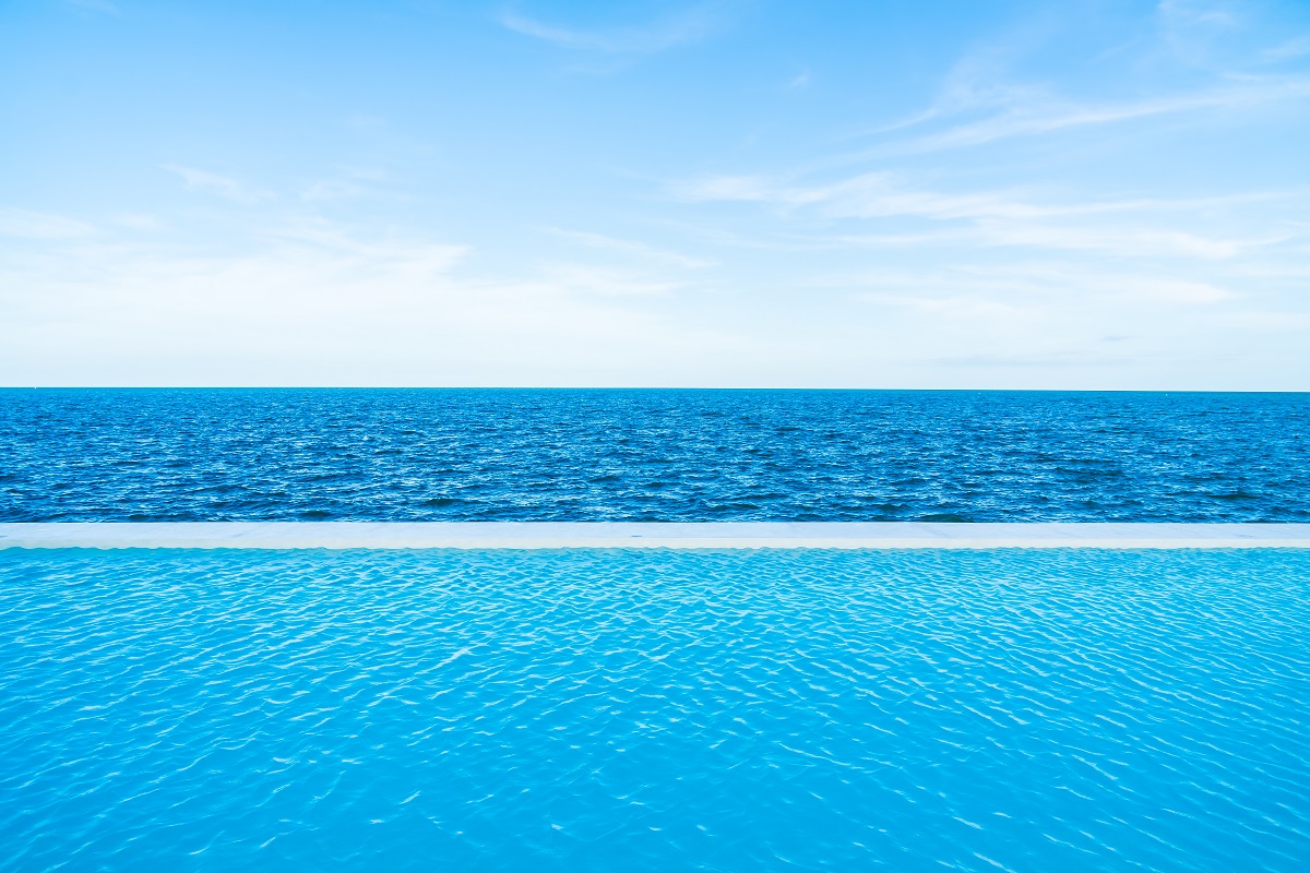 Infinity Swimming Pool With Sea And Ocean View On Blue Sky
