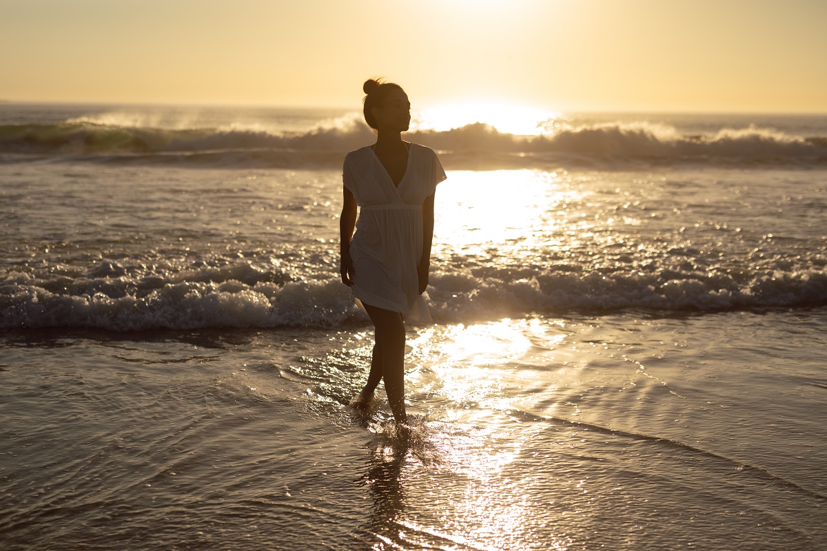 Thoughtful Woman Walking On Sea At Beach