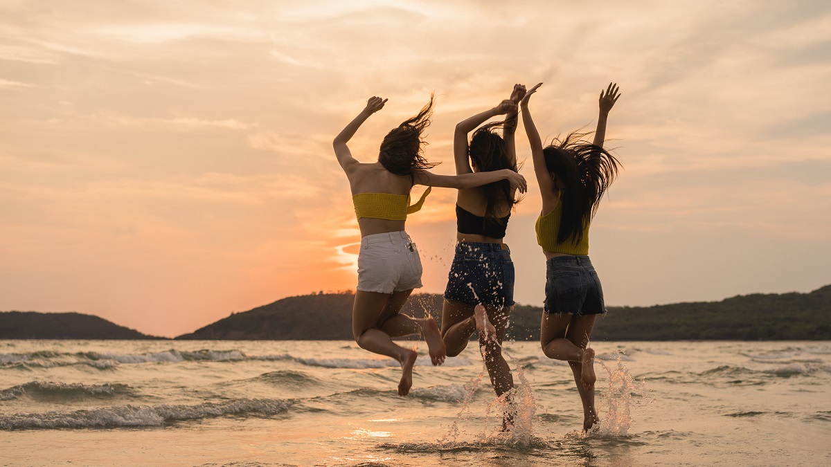 Group Of Three Asian Young Women Jumping On Beach, Friends Happy
