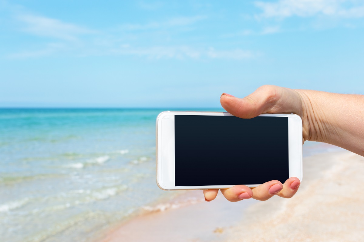 Beautiful Woman's Hand Using Smart Phone At Beach